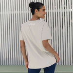 A back view of a woman wearing a sandy-coloured oversized tee. The "Active Elite" logo is clearly visible on the back, and the tee’s relaxed fit is perfect for a comfortable workout.
