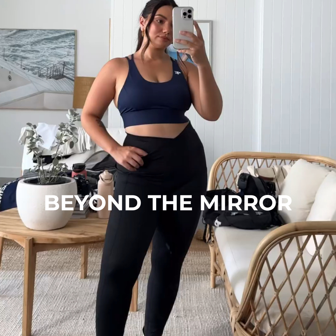 Image of a woman standing in front of a mirror taking a photo of herself dressed in Active Elite activewear.