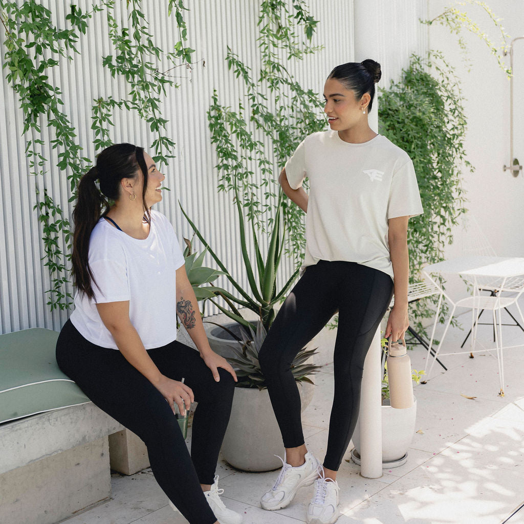 Two women smiling and engaging in conversation, enjoying a moment of connection and positivity.