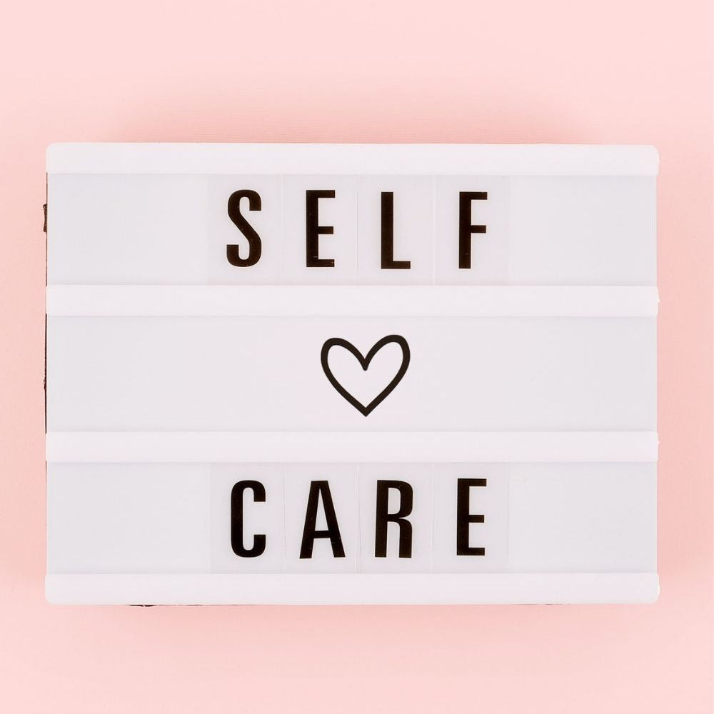 Graphic image of a light board with words "self" and "care" and a heart on a pink background