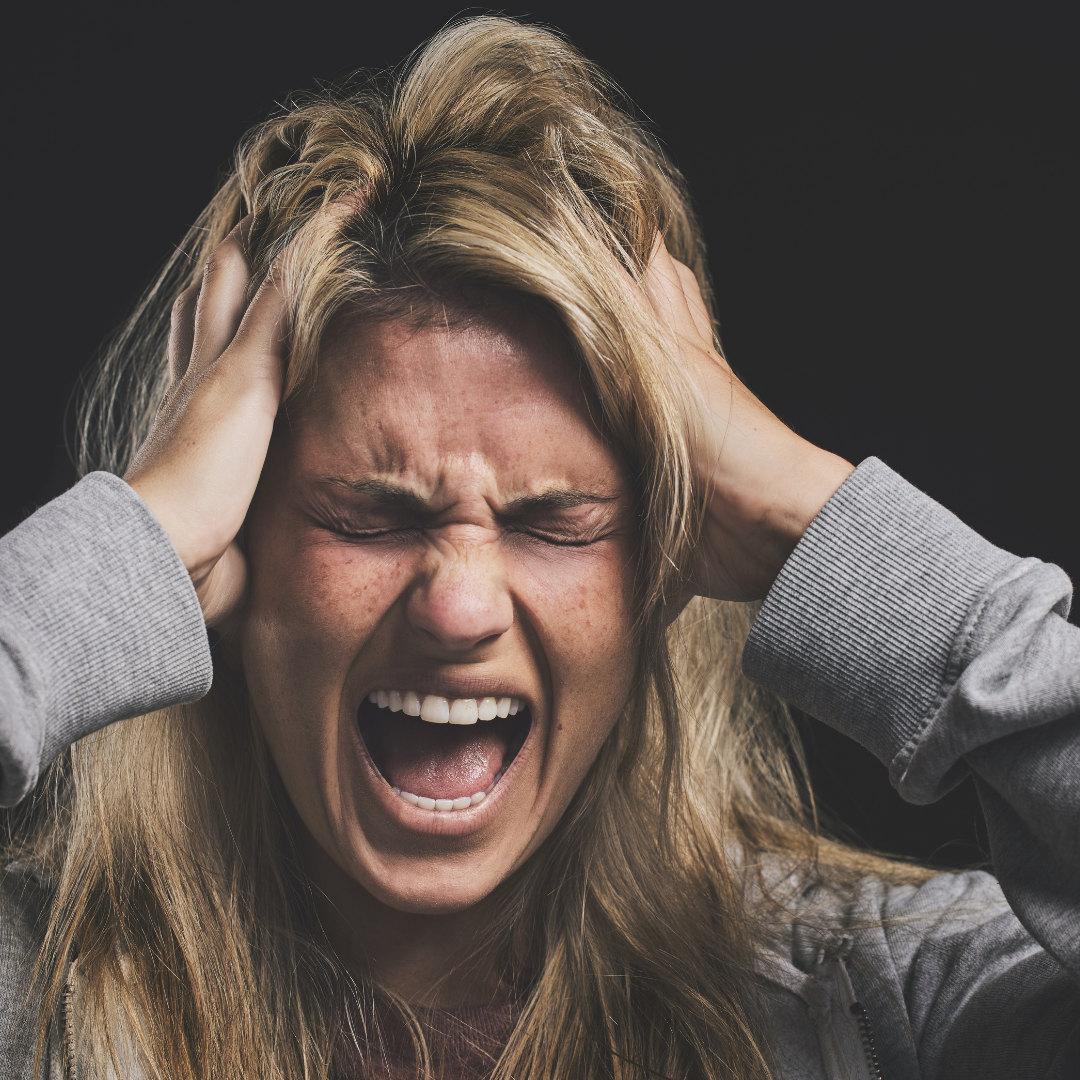 A distressed woman gripping her head, symbolizing stress or frustration, with a focus on mental health challenges.