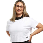 A woman smiling in a white cropped fitness top, exuding confidence and comfort in activewear.