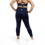 A back view of a woman in navy high-waisted leggings, highlighting the contoured design and Active Elite logo.