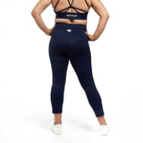 A back view of a woman in navy high-waisted leggings, highlighting the contoured design and Active Elite logo.