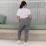 A woman from behind wearing grey leggings and a white cropped tee.