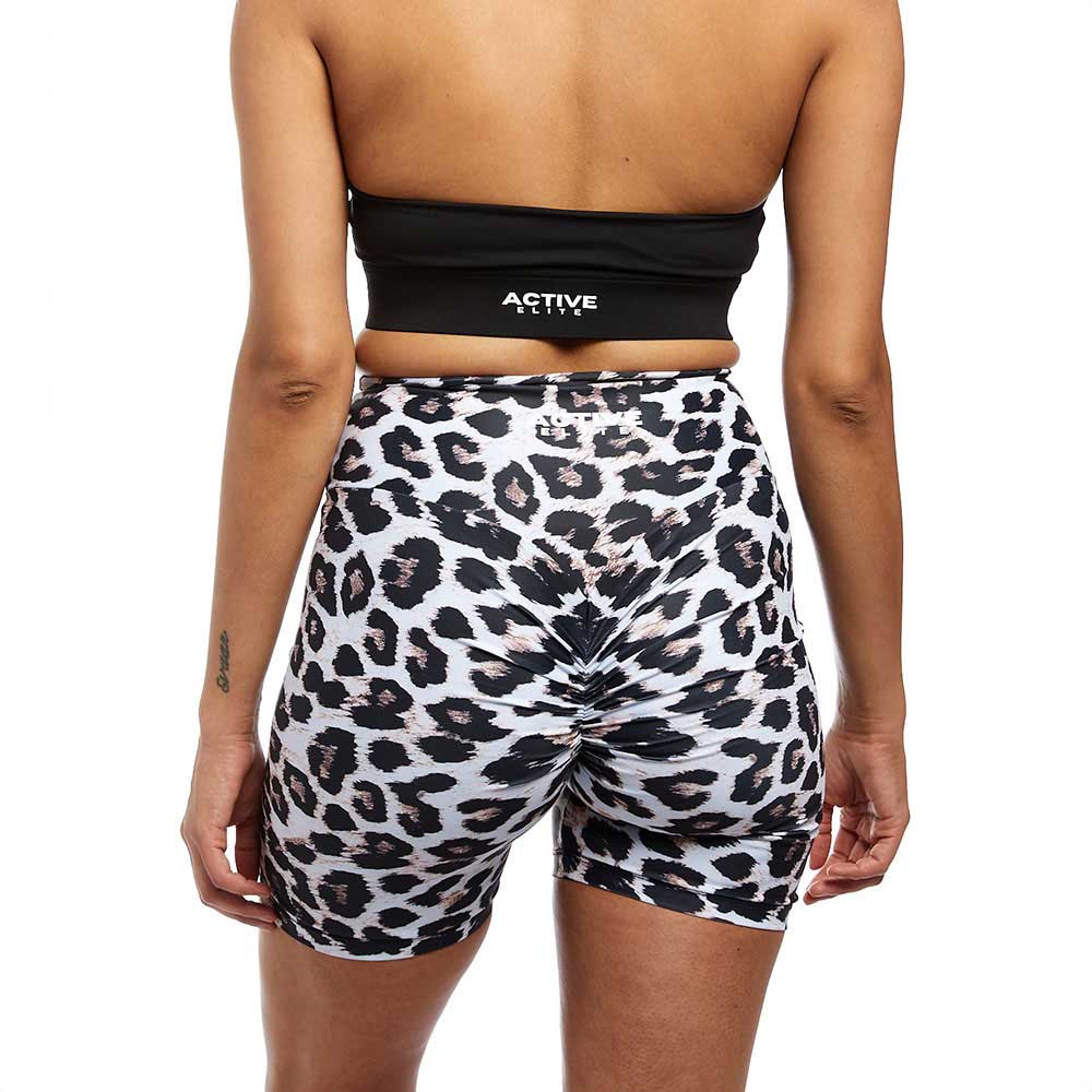 A back view of a woman wearing leopard-print scrunch-back shorts and a black crop top. The close-up emphasizes the form-fitting, stylish design of the activewear set.